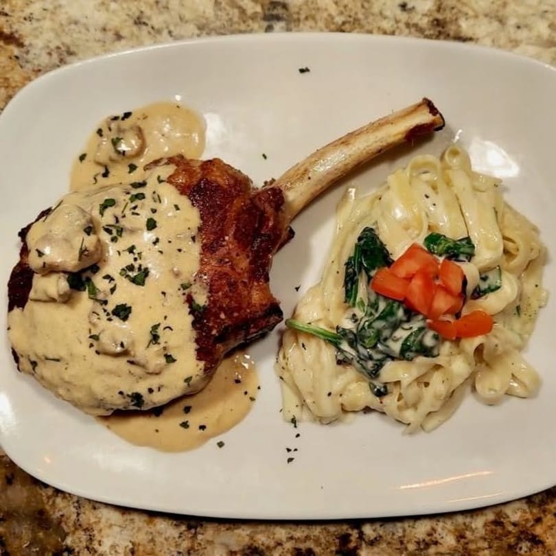Bone-in chop with creamy mushroom sauce and fettuccine alfredo with spinach and diced tomatoes.